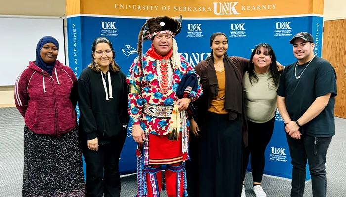 students from the FNSA group pose with a speaker in traditional native american dress