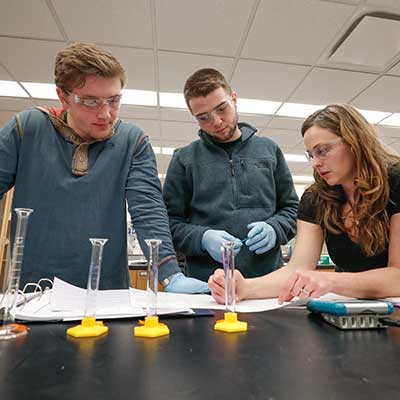 Students performing a science experiment with a professor