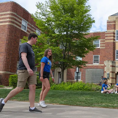 students walk past a dorm building on a sunny day