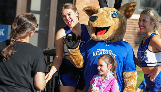 a child poses with unk cheer leaders and louie the loper