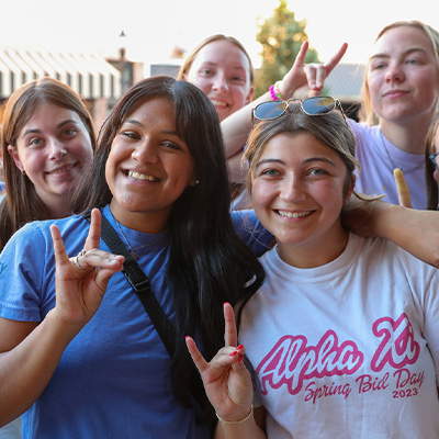 students pose for a photo outdoors, throwing their lopes