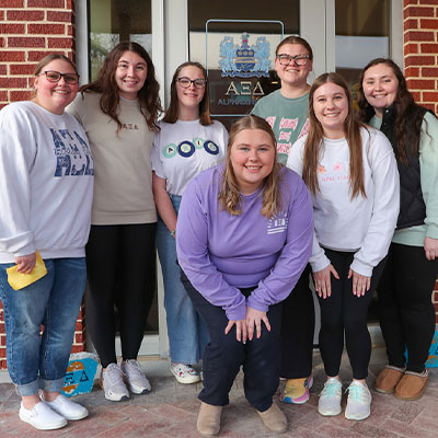 students pose outside the door of armstrong hall