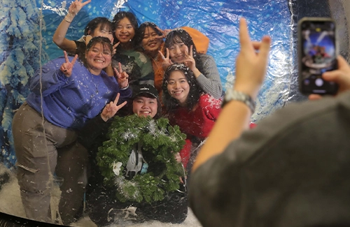 students pose for a photo in a blow up snow globe at the Gingerbread House Competition