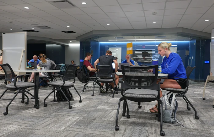 students sit at tables with signs indicating different subjects
