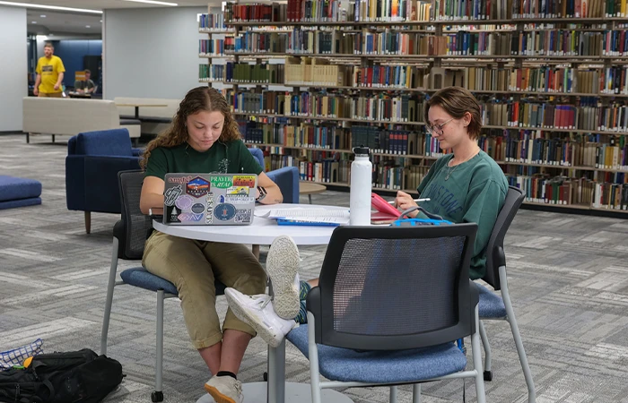 two students sit at a table together in the library