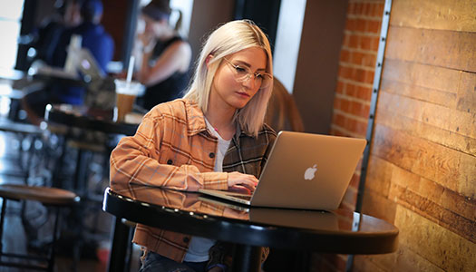 a woman sits at a counter looking at a laptop