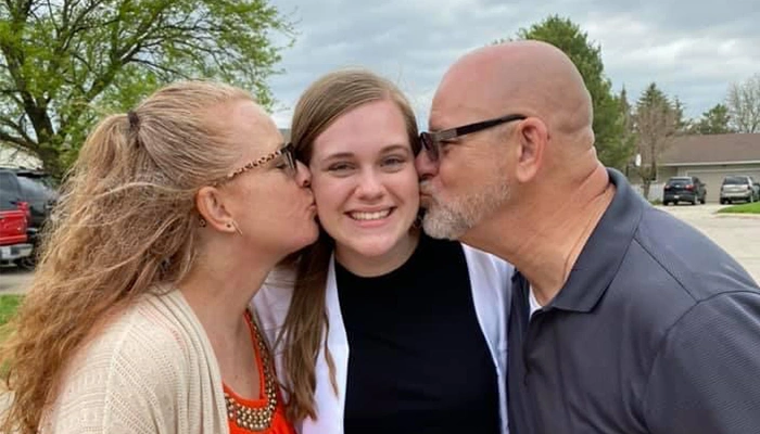 Carly Holbrook poses for a photo with her parents