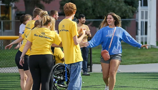 a student is greeted by a group in yellow shirts
