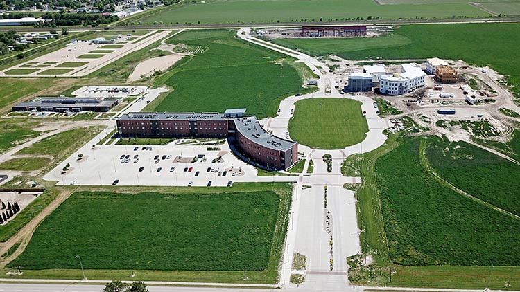 Arial view of University Village showing the completed Plambeck Center and Village Flats Apartments as well as under construction projects Element 30 apartments and the Tennis Complex.