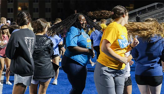 Students dance on the football field at night 