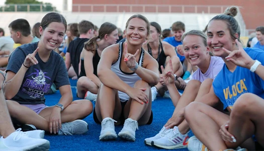 Students sit at an outdoor event and throw the lopes