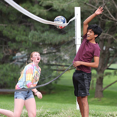 Students playing sand volleyball at party in the park