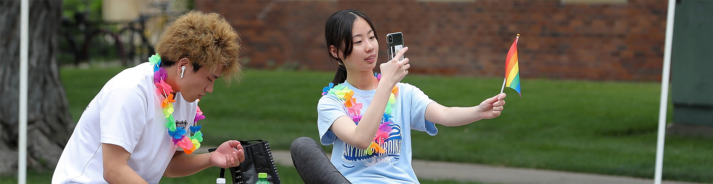 a student takes a picture of a pride flag at a pride month celebration event