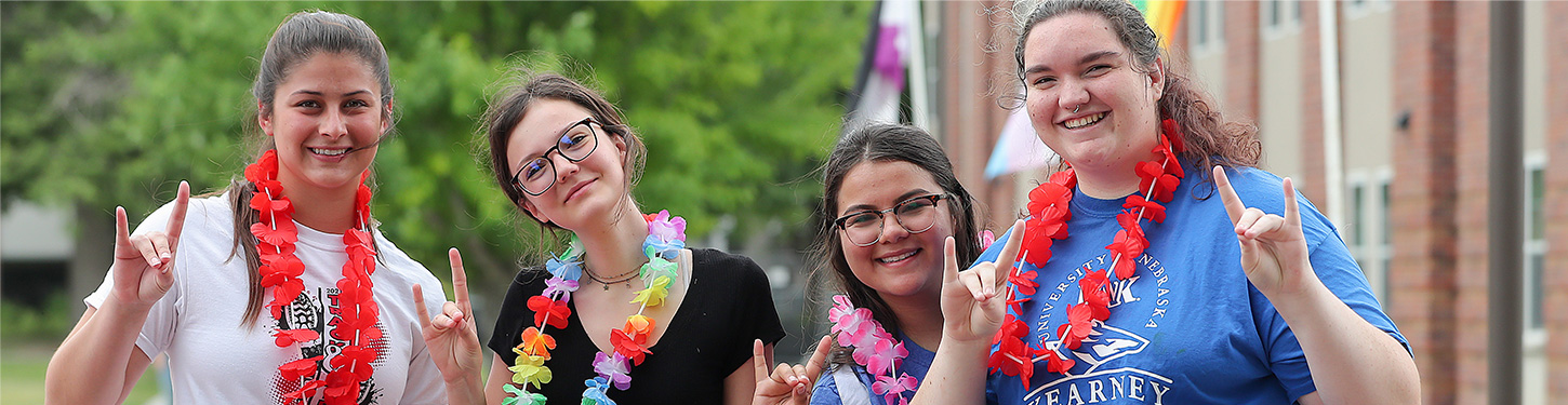 Four students pose for a picture at a pride month event