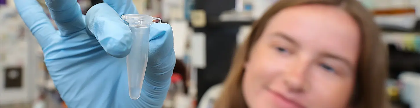 A student holds a vial in a gloved hand