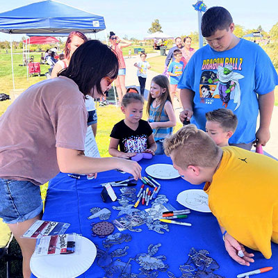 a frank house volunteer interacts with children at a community partners event