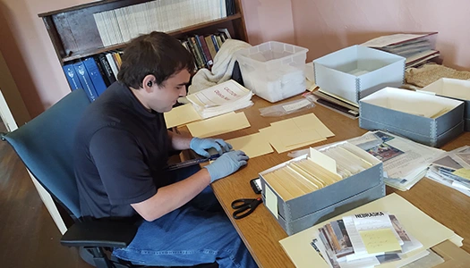 an intern files archive information at a desk in the frank museum