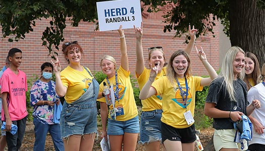 Students leaders welcome new students at a move in event, holding up a sign that reads herd 4 Randall 3 